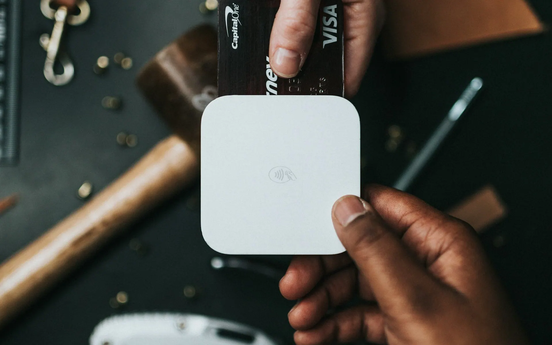 Hand holding a small white contactless payment reader