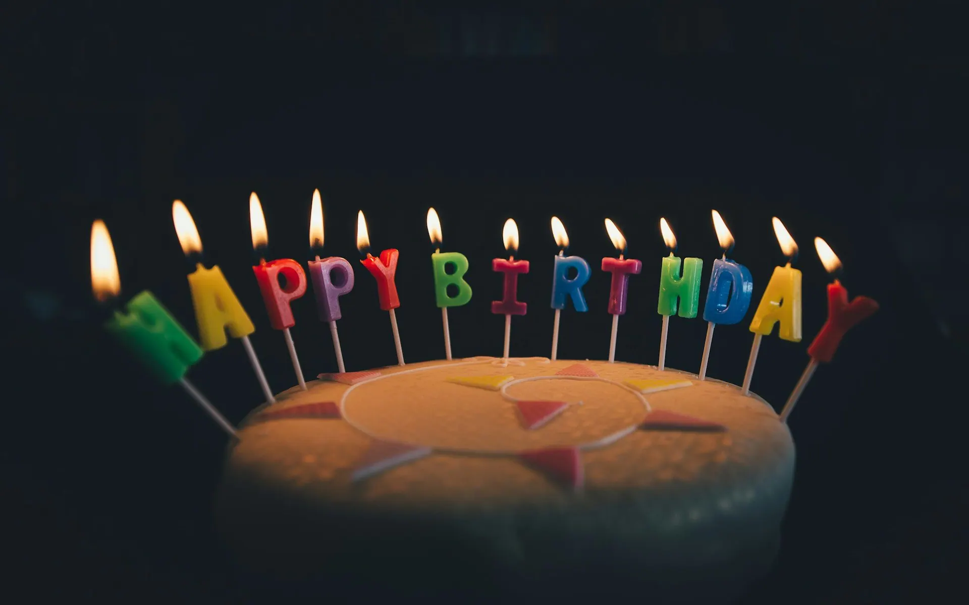 Lit “Happy Birthday” candles on a cake