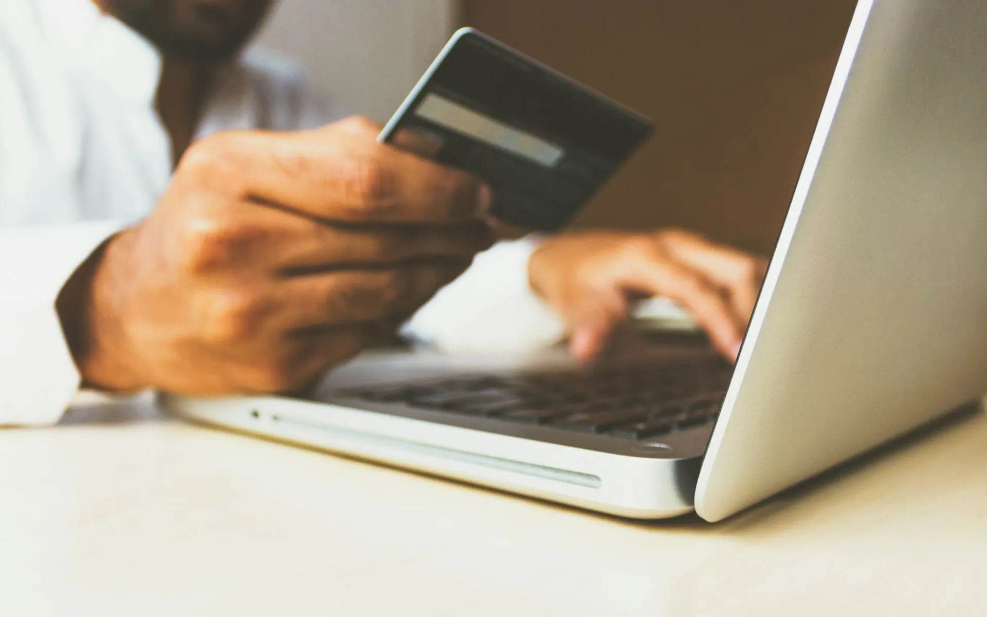 Person holding a payment card while using a laptop