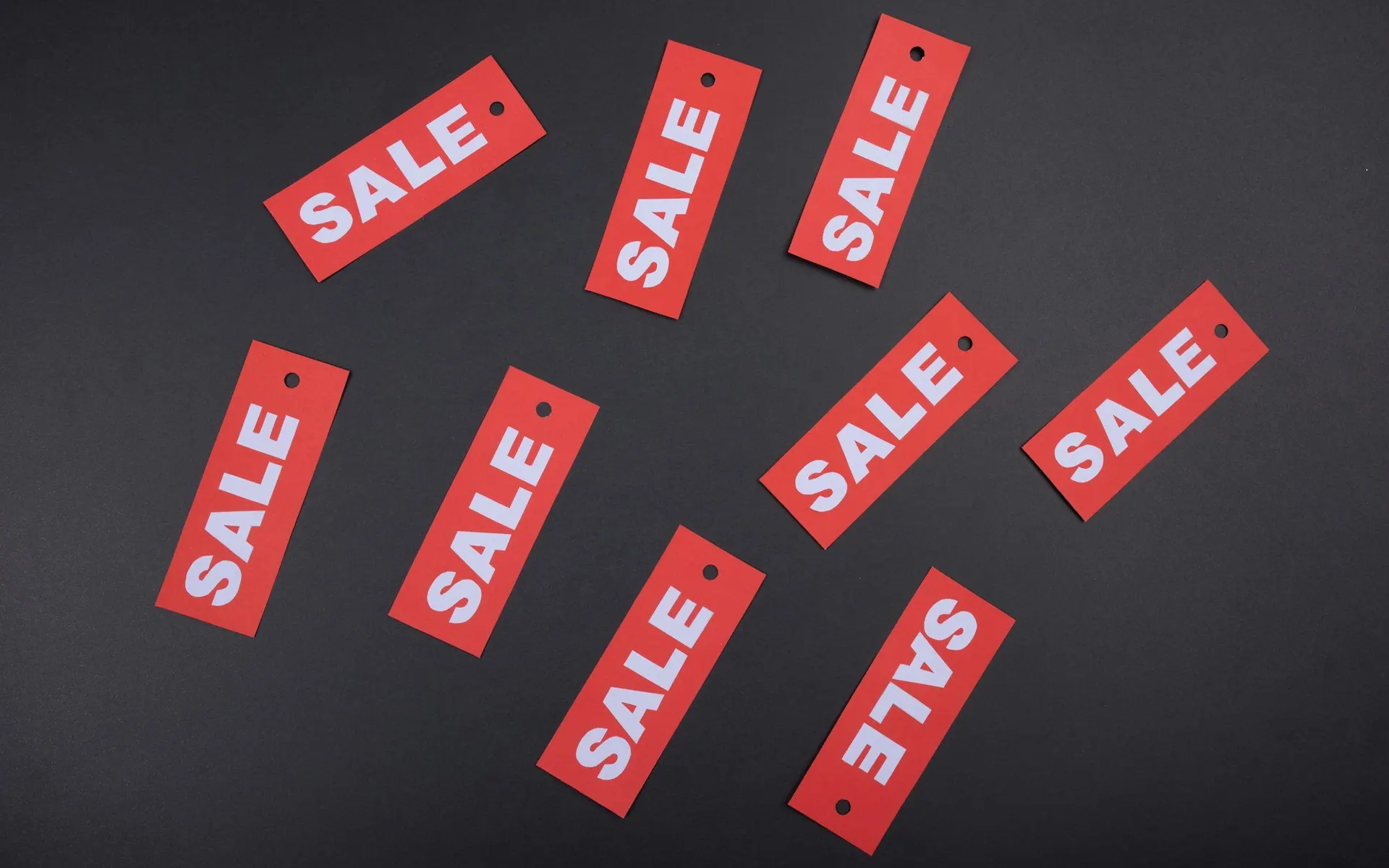 Red sale tags scattered on a dark surface